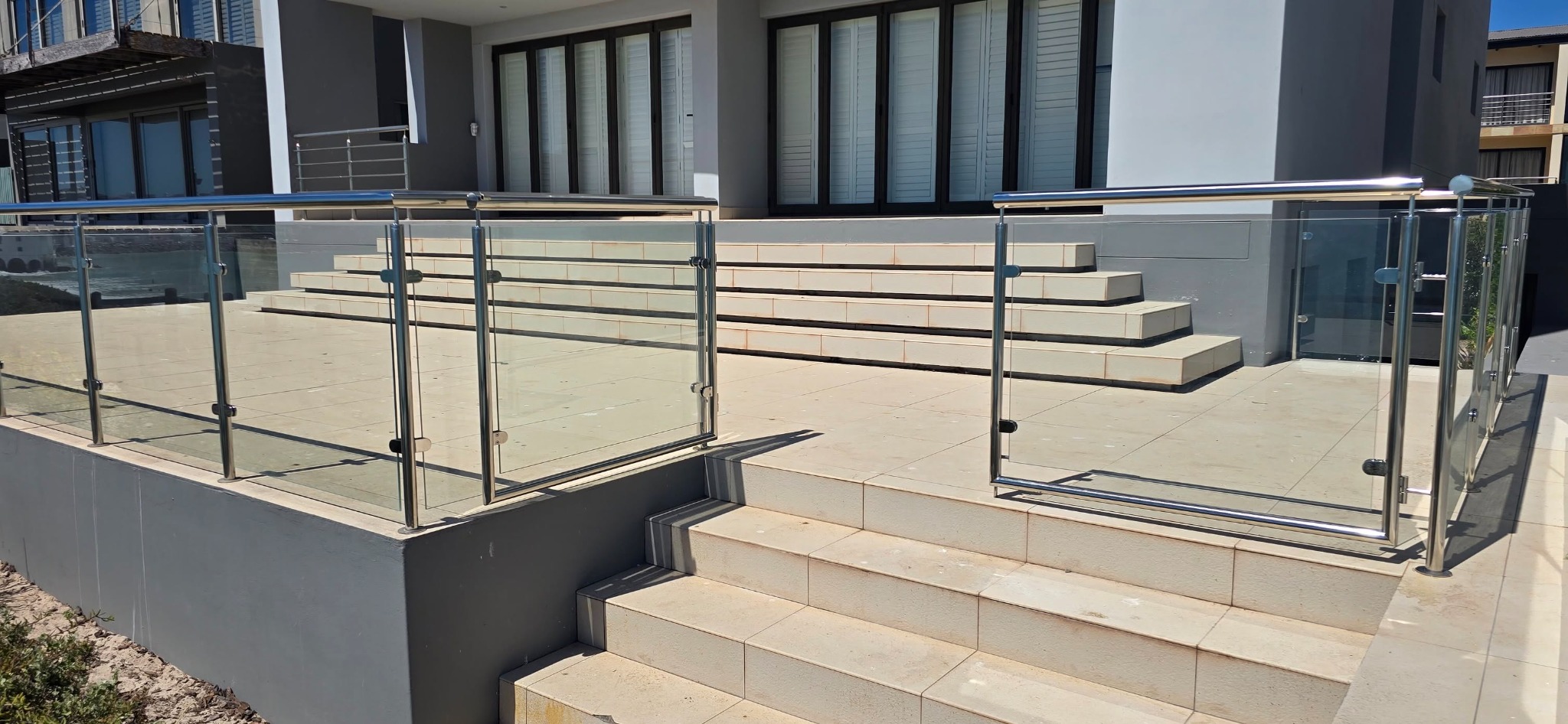 Glass and stainless steel balustrades around a coastal home terrace